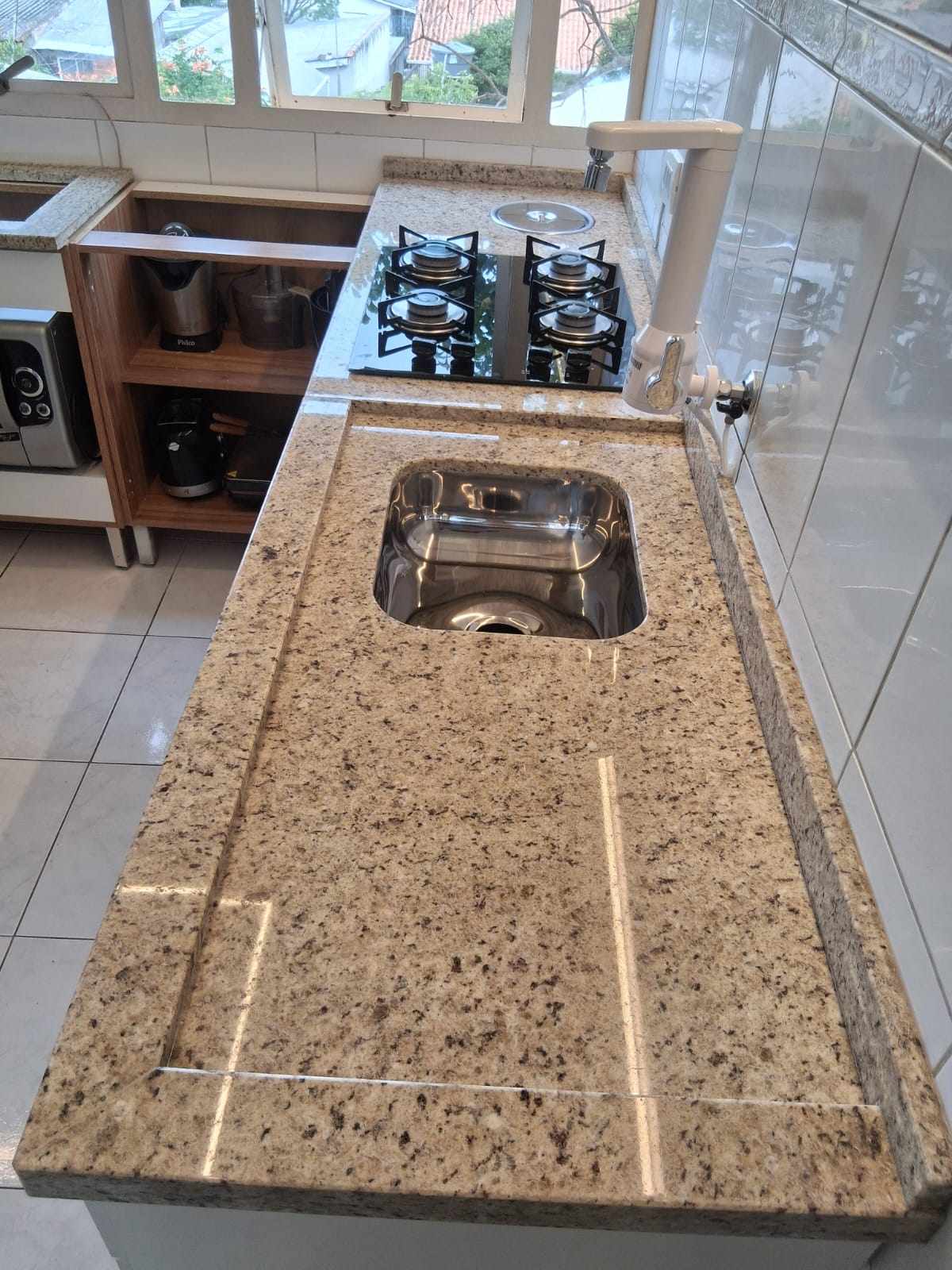Bancada de granito claro com cooktop e cuba em cozinha real da Art Bella